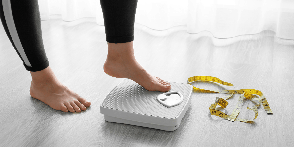A woman stepping on a scale.